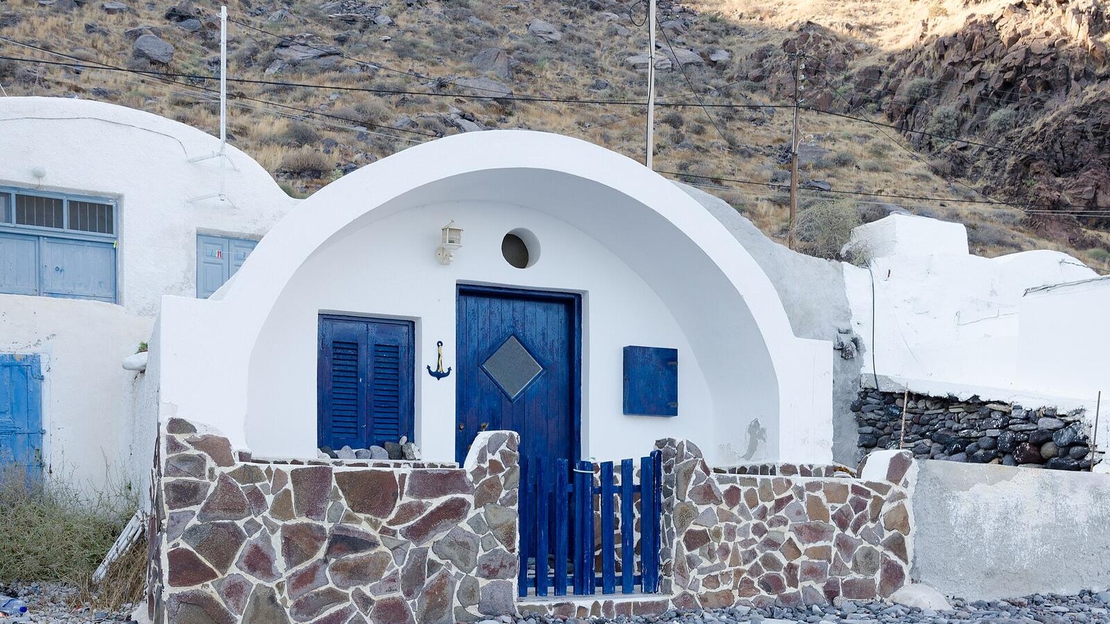 Witte vissershuisjes met blauwe deuren bij het haventje Korfos op Thirassia