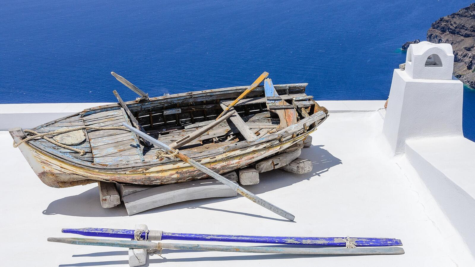 Een oude roeiboot als decoratie op een wit dak in Fira