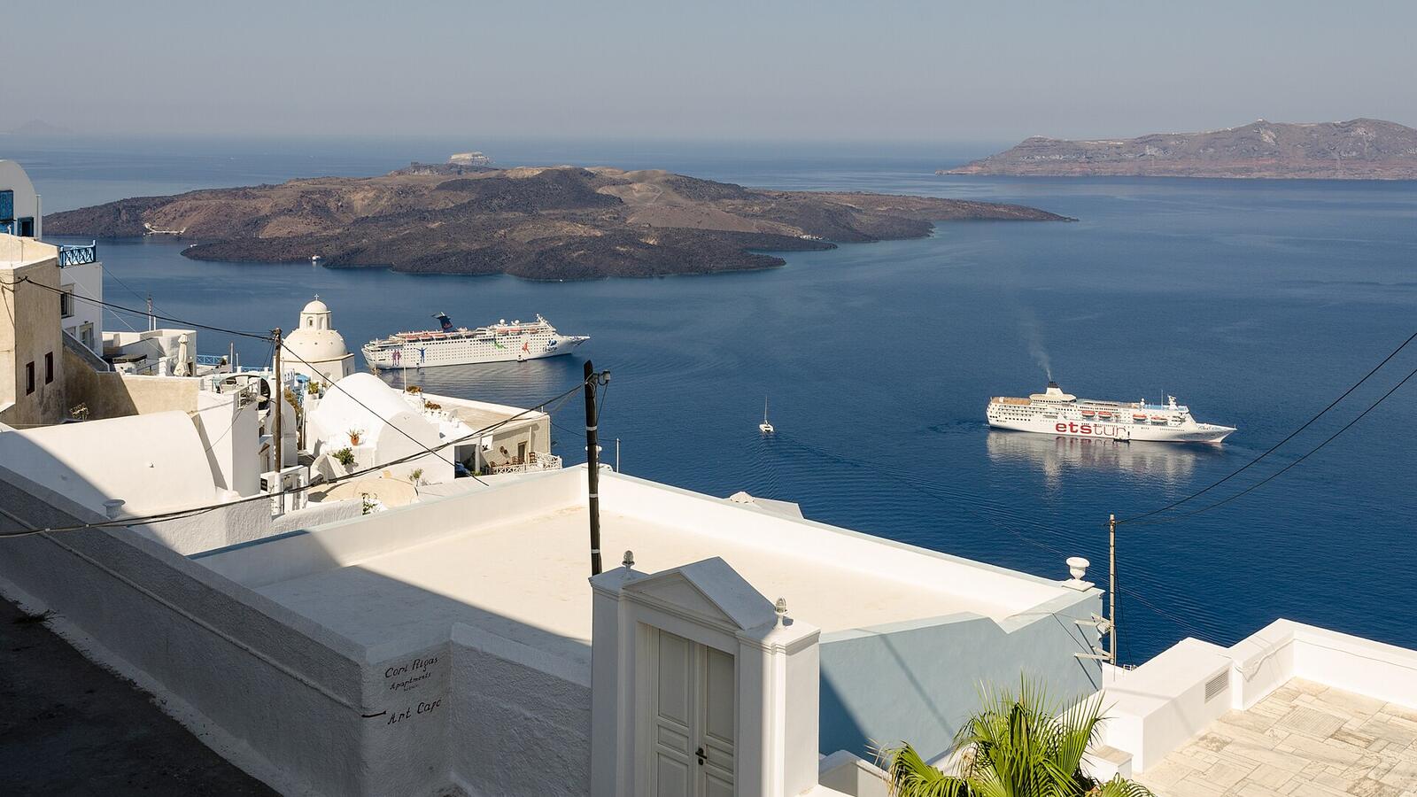 Witte terrassen in Fira met uitzicht over de caldera en een cruiseschip in de verte
