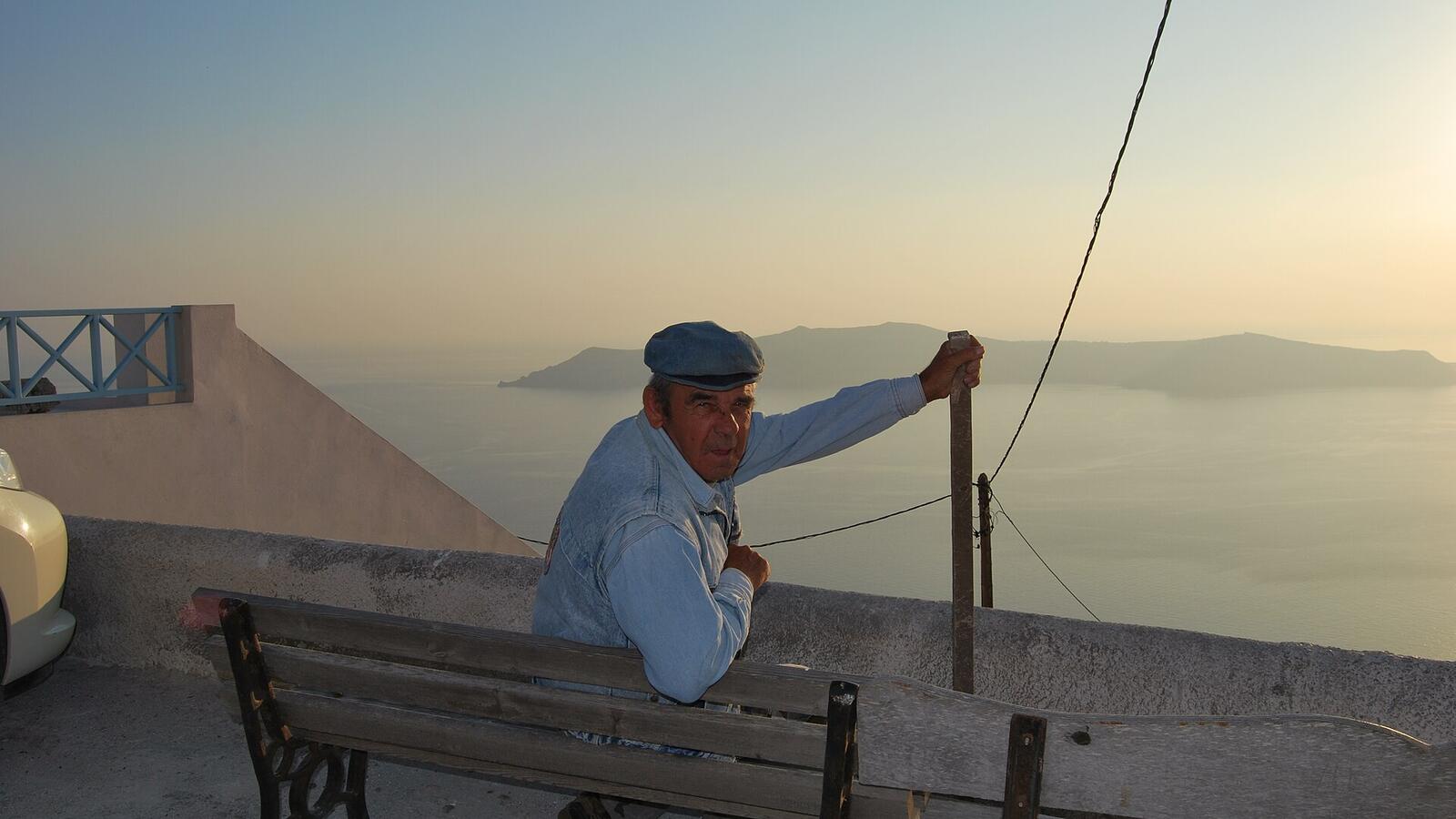 Een man op een bankje in Imerovigli bij zonsondergang boven de caldera