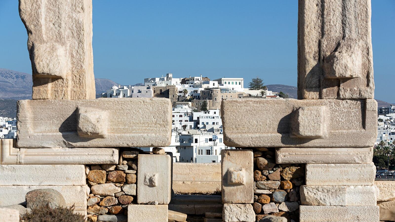 De marmeren poort van de Portara op Naxos met de stad op de achtergrond