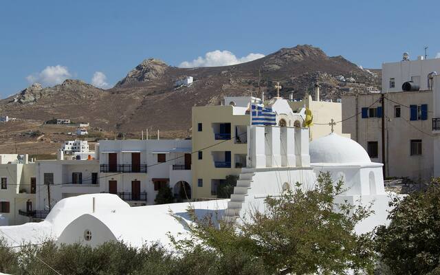 Witte huizen en een kerk in Naxos-stad tegen de bergen