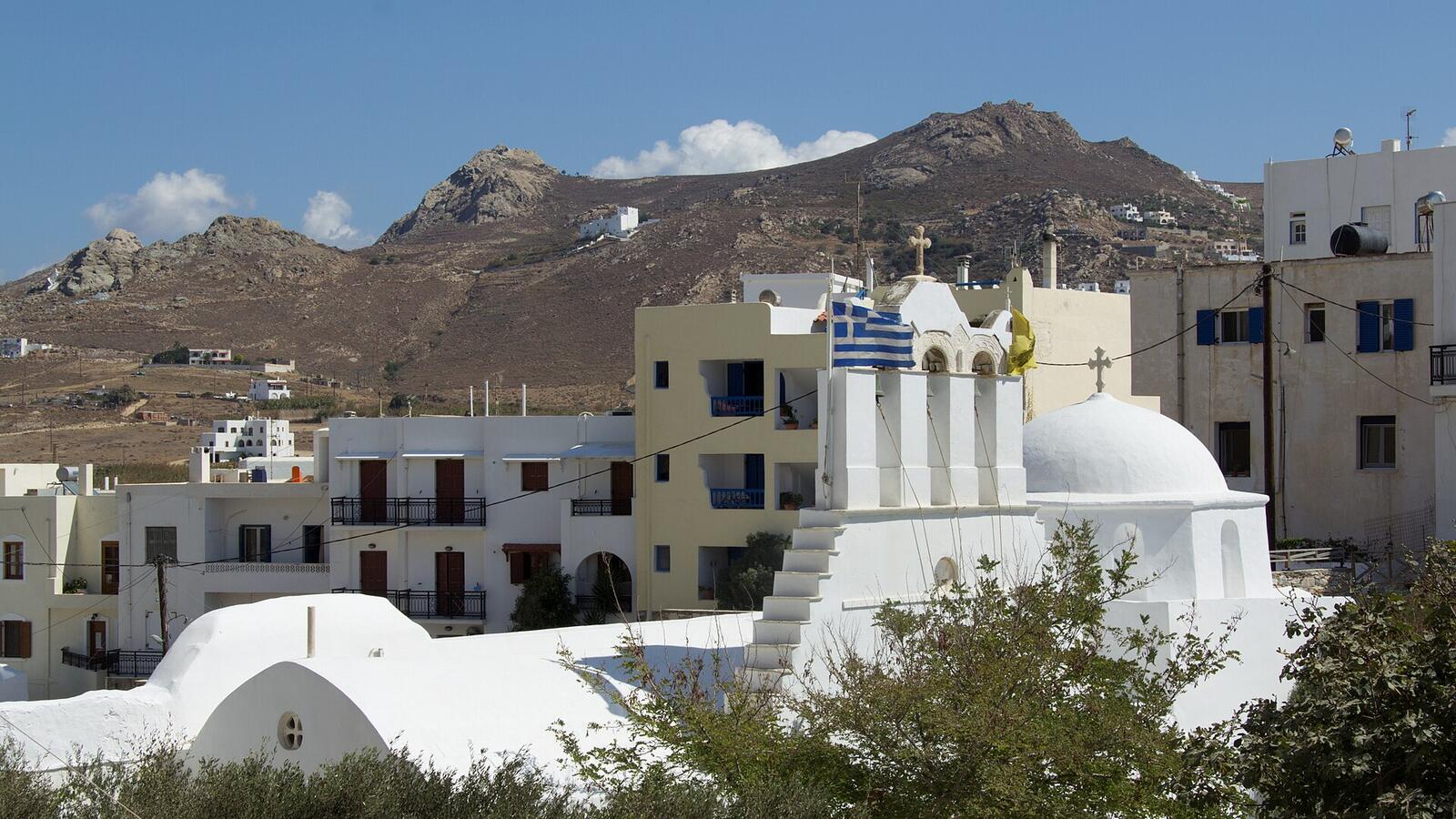 Witte huizen en een kerk in Naxos-stad tegen de bergen