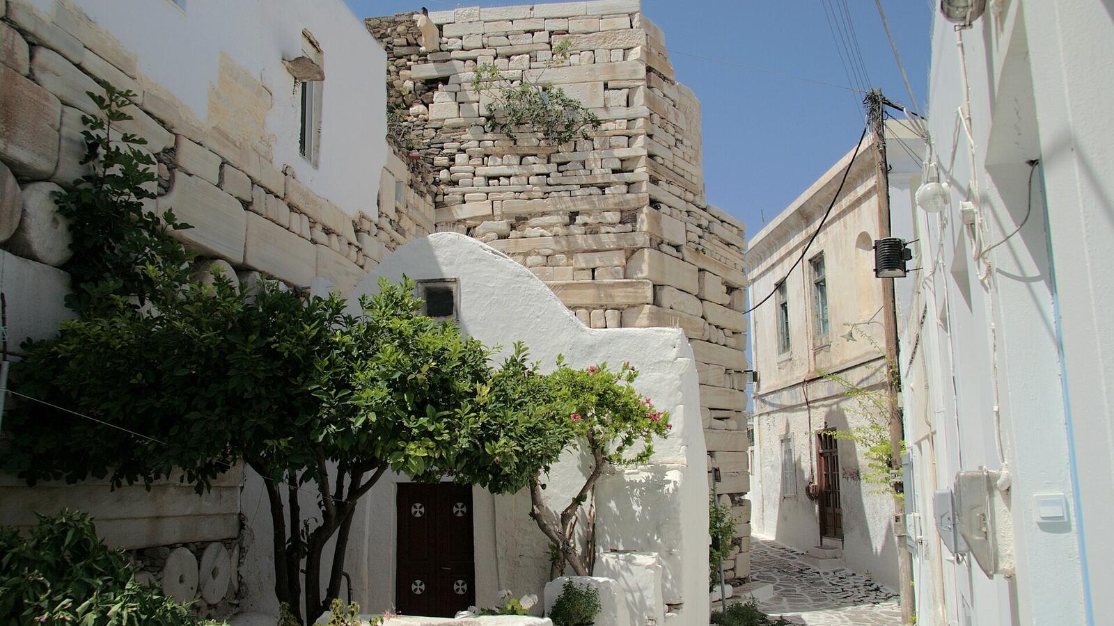 Steegje met witte muren en een oude toren in het Kastro van Parikia op Paros
