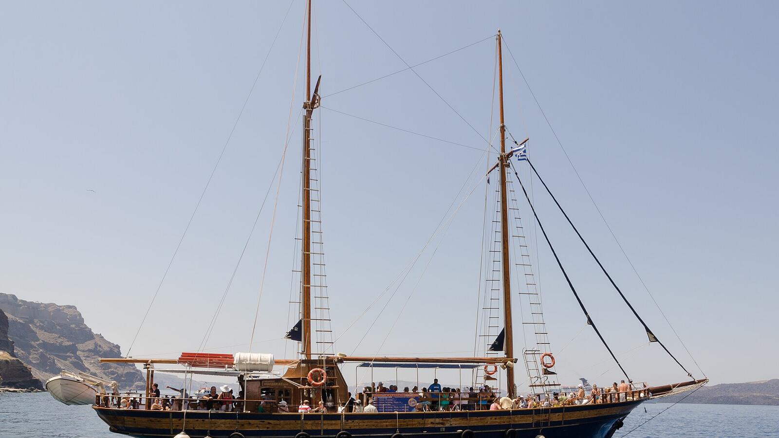 Rondvaartboot in de oude haven van Fira onder de calderawand
