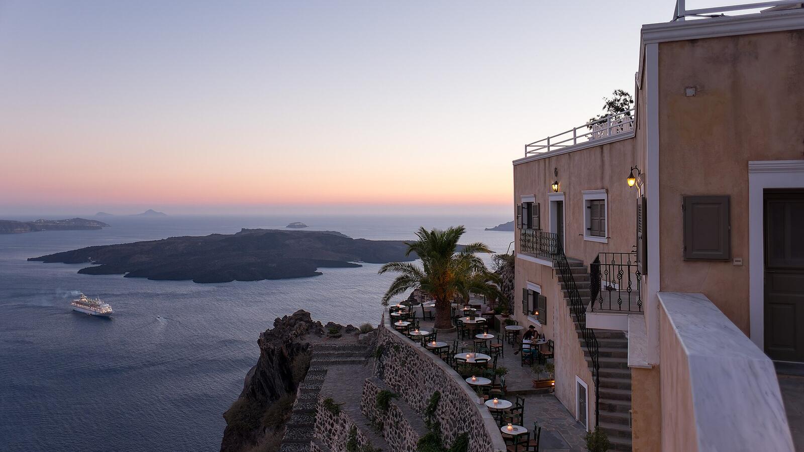 Restaurantterras in Fira bij zonsondergang boven de caldera